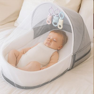 Bébé souriant allongé dans un lit de voyage bébé compact gris avec moustiquaire transparente, dans une chambre lumineuse au ton beige.