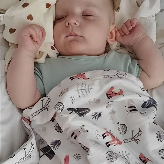 Bébé endormi sous une couverture douce à motifs forestiers – sommeil paisible et cocooning pour bébé.