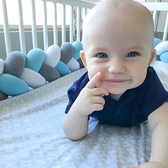 Tresse de lit bébé multicolore utilisée dans un berceau moderne, garantissant confort et style à la chambre.