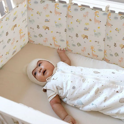  Bébé dormant paisiblement dans un lit équipé d’un tour de lit à motifs animaux pour plus de sécurité et de confort