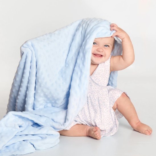 Bébé souriant couvert d’une couverture douce bleue en tissu Minky – confort et chaleur après le bain