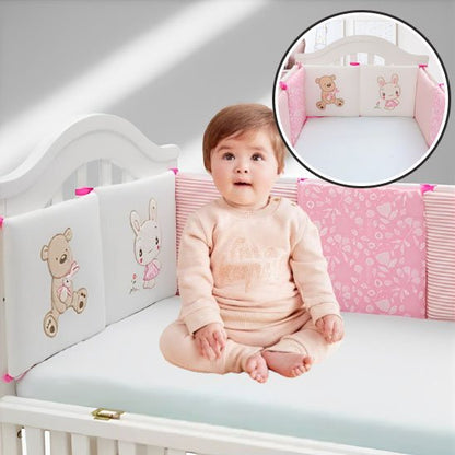Bébé souriant assis dans un lit avec tour de lit rembourré rose et motif d’ourson brodé – confort et tendresse.