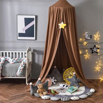 Ciel de lit bébé marron au-dessus d’un berceau entouré de peluches, parfait pour une chambre cocooning