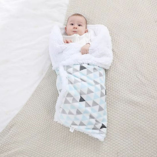  Bébé allongé paisiblement sous une couverture blanche et grise à motifs géométriques, parfaite pour la sieste