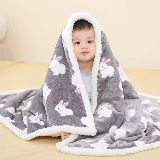 Bébé enveloppé dans une couverture grise ultra douce avec motifs de lapins blancs – idéale pour garder votre enfant au chaud et confortable