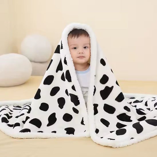 Bébé assis avec une couverture pelucheuse à motifs animaux noirs et blancs – parfaite pour les moments de détente et de jeu