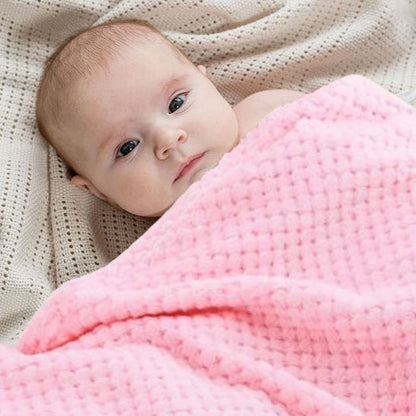 Bébé éveillé regardant la caméra tout en étant enveloppé dans une couverture rose confortable