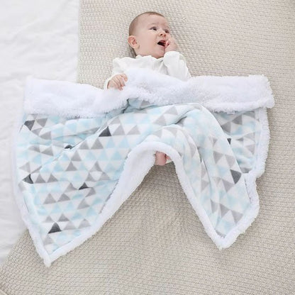 Bébé souriant enveloppé dans une couverture moelleuse à motifs triangles gris, douce et chaude pour l’hiver