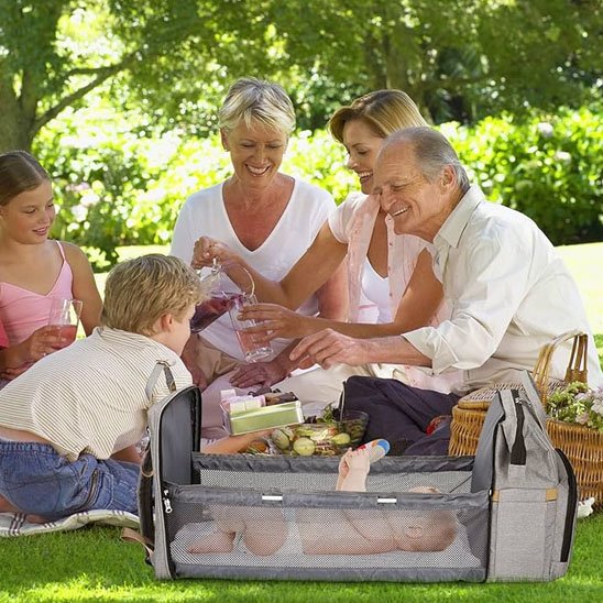  Famille heureuse profitant d’un pique-nique avec un sac à langer multifonction gris posé à côté, parfait pour les sorties avec bébé.