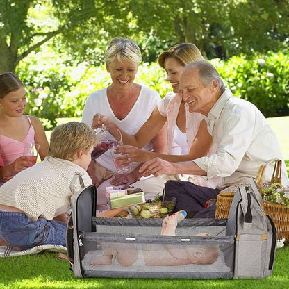  Famille heureuse profitant d’un pique-nique avec un sac à langer multifonction gris posé à côté, parfait pour les sorties avec bébé.