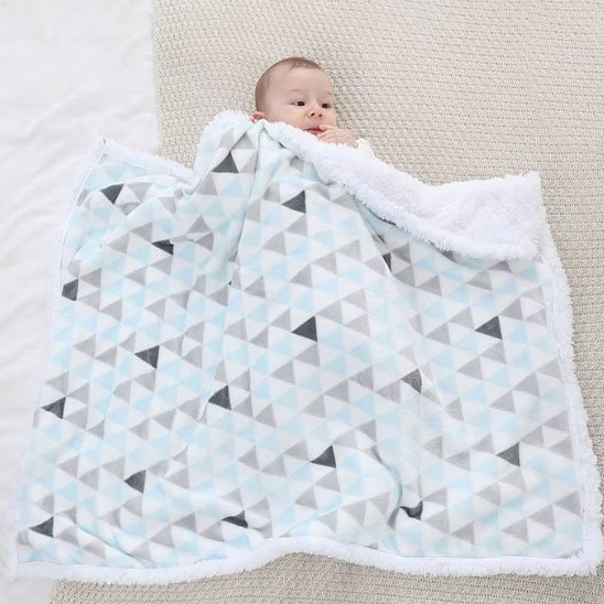 Bébé assis sur une couverture design à triangles colorés, combinant douceur et élégance moderne