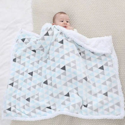 Bébé assis sur une couverture design à triangles colorés, combinant douceur et élégance moderne