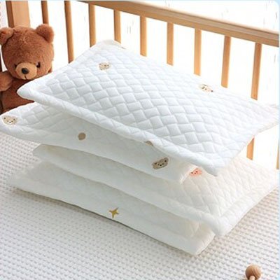 Pile d’oreillers pour bébé en coton blanc, avec jolis motifs d’oursons brodés – confort et douceur pour le sommeil de bébé.
