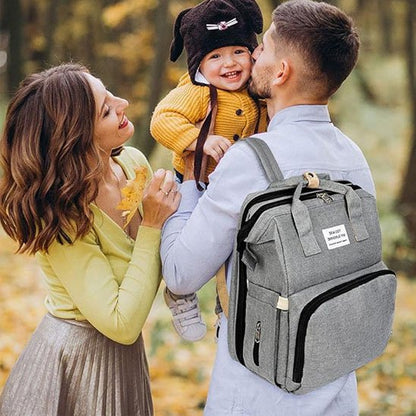  Papa portant un sac à langer moderne sur le dos tout en jouant avec son bébé, design élégant et pratique pour les voyages.