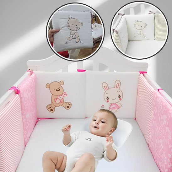 Bébé allongé dans un lit équipé d’un tour de lit rose avec motifs d’ourson et de lapin – sécurité et confort pour le sommeil de bébé.