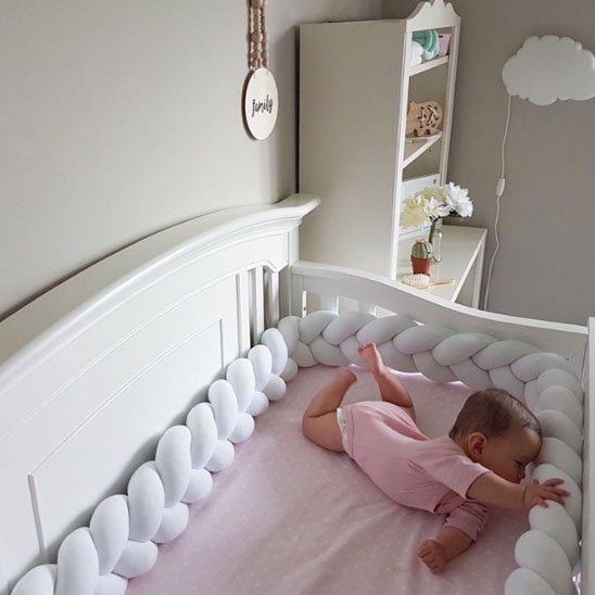 Tresse de lit bébé grise installée dans un berceau, offrant une protection douce et sécurisée pour le sommeil.